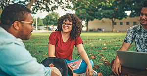 3 students with laptop on the meadow